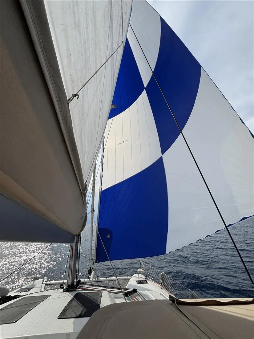 Blue and white spinnaker flying over the bow of a catamaran